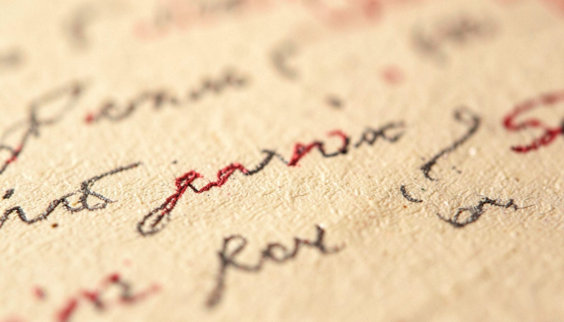 Extreme close-up of handwritten notes on textured cream paper with soft graphite pencil marks and warm ambient light